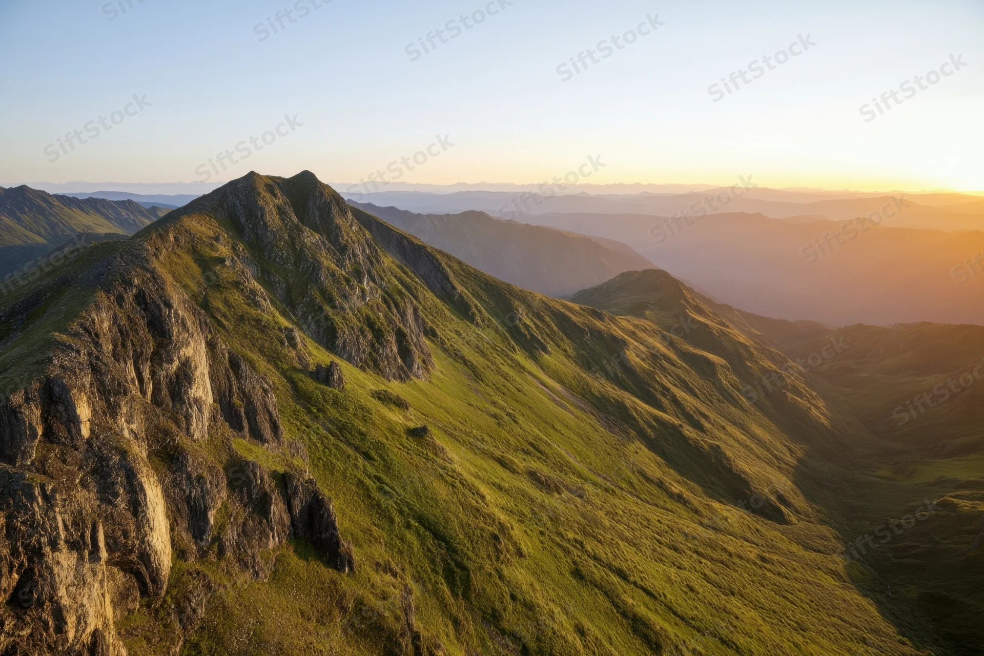 Panoramic view of rugged mountain peaks and green valleys at sunset