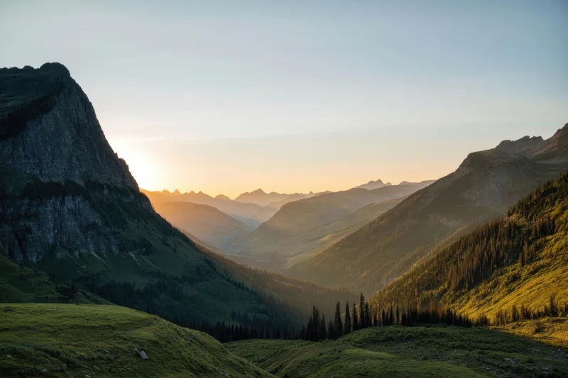 Panoramic mountain valley at sunset with rugged cliffs and lush green slopes