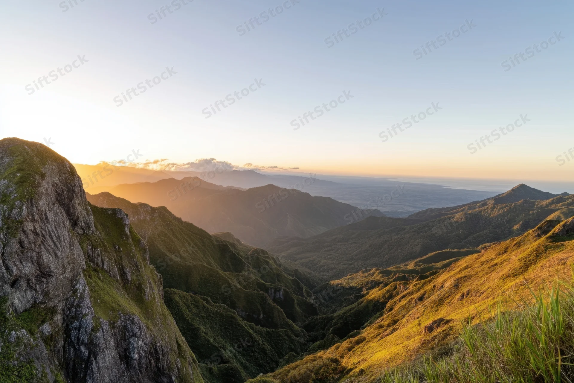 Panoramic view of a mountain valley at sunset with rugged cliffs and lush slopes