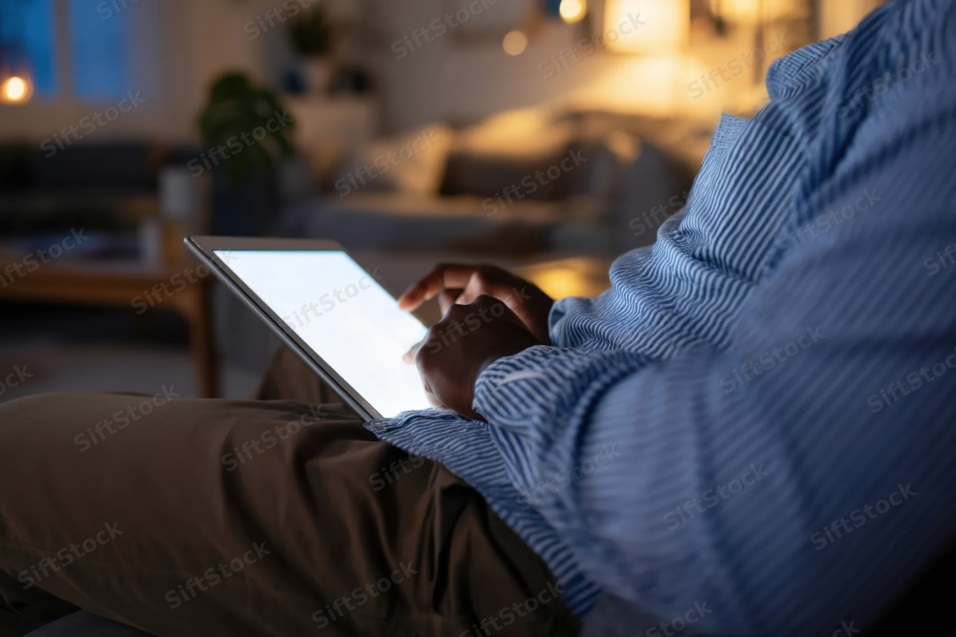 Man using tablet while sitting on couch in dimly lit living room
