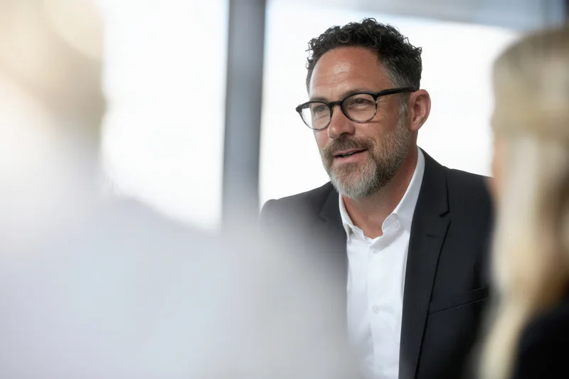 Man in suit and glasses speaking during a business meeting in an office