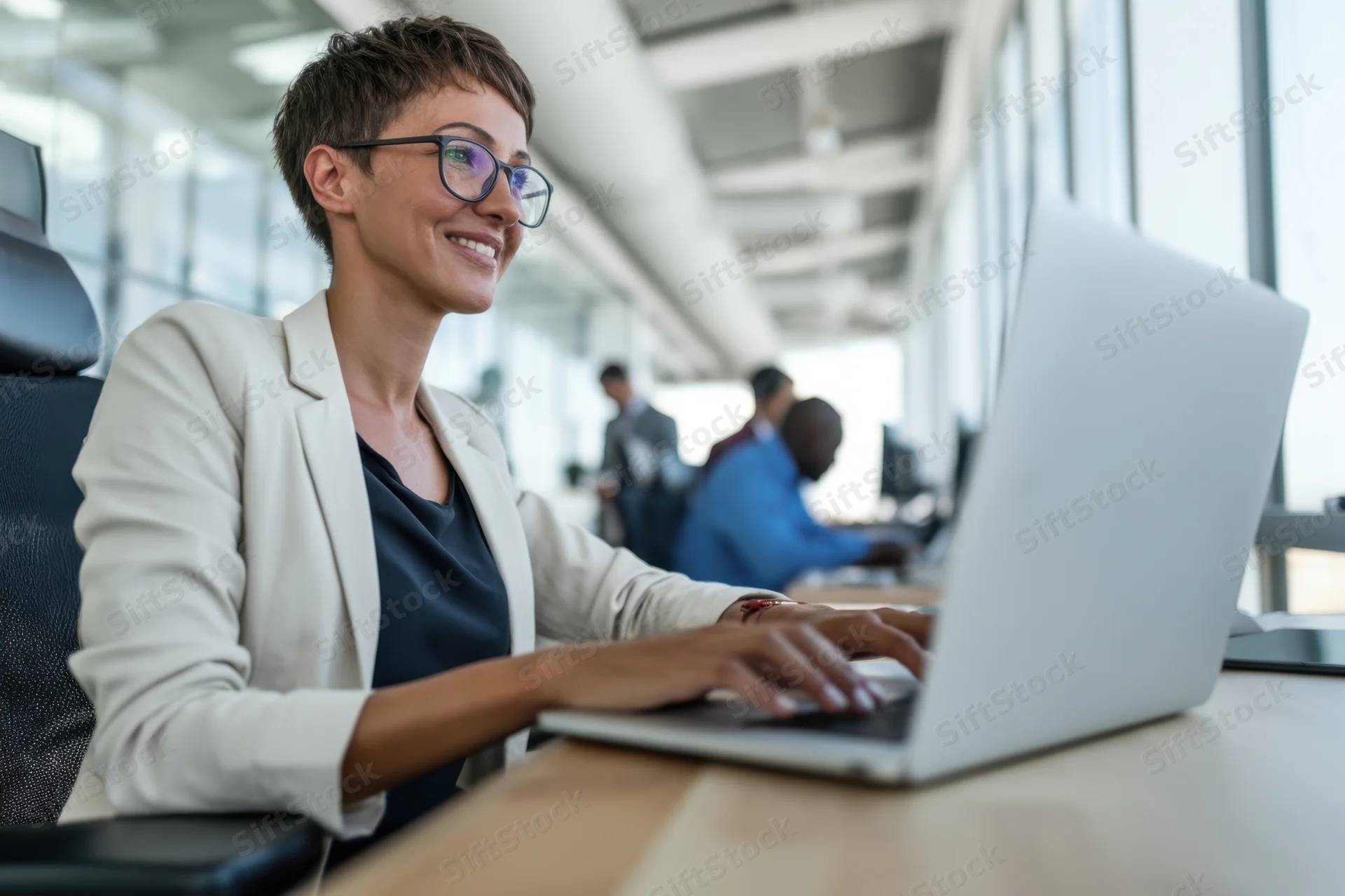 Woman smiling while typing on laptop at office desk