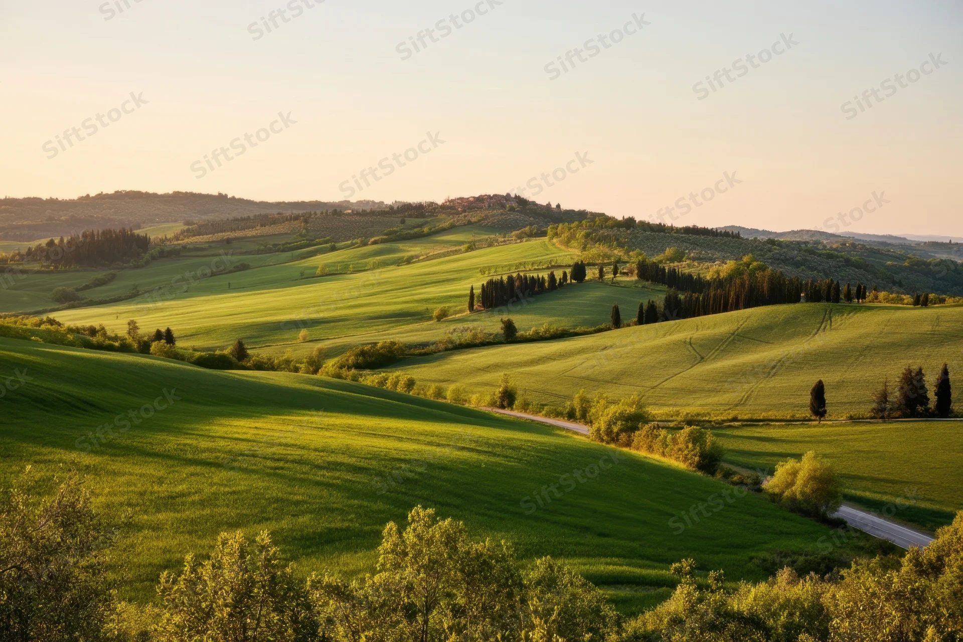 Sunlit rolling green hills and patchwork fields in rural landscape