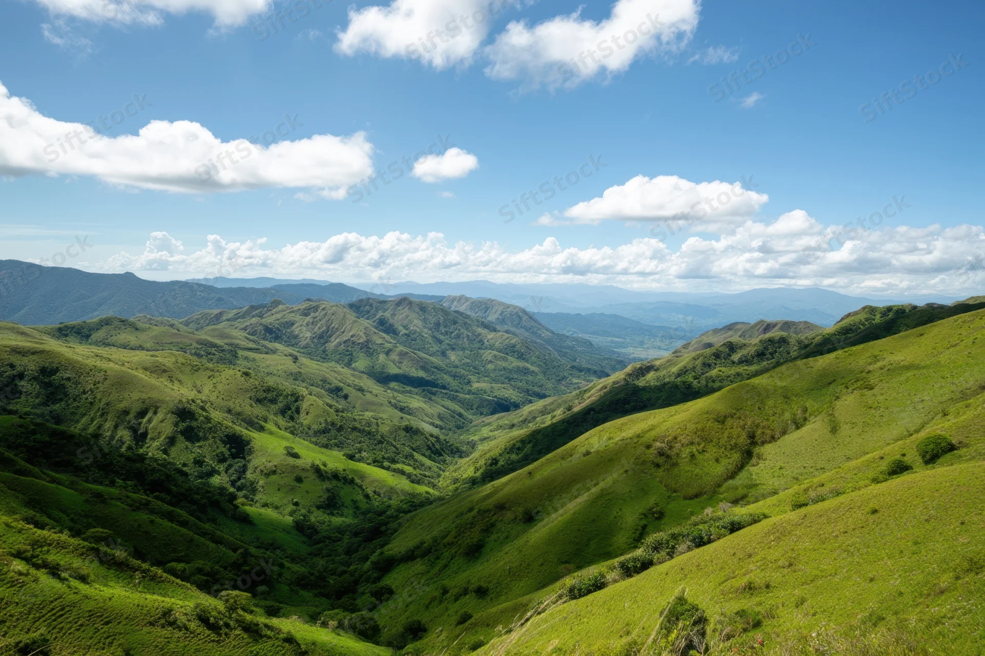 Rolling green hills forming a valley under a bright blue sky with scattered clouds