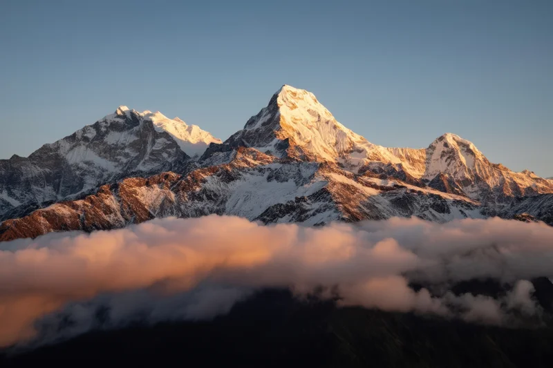 Snow-capped mountain peak rising above a sea of clouds at sunrise