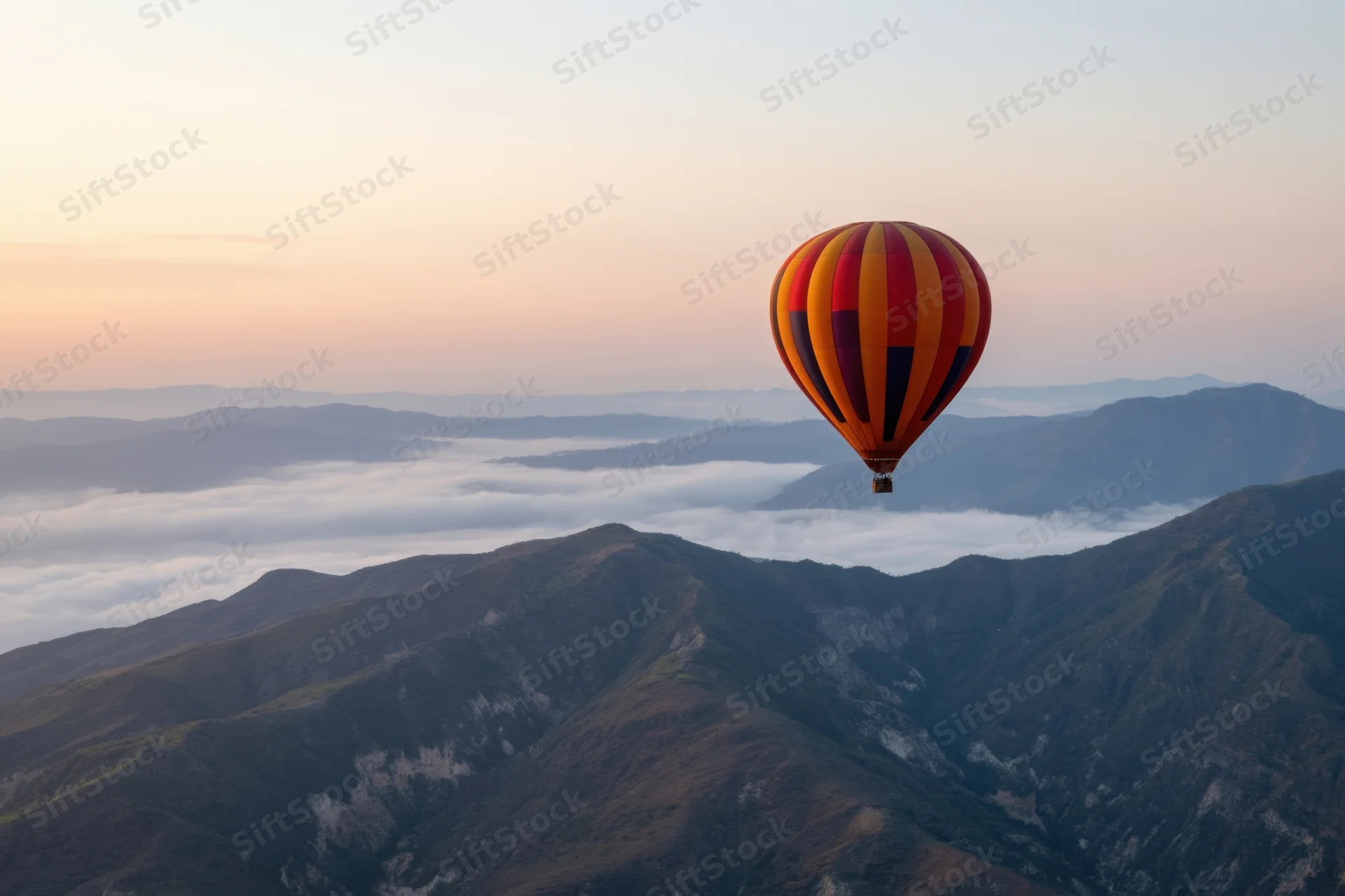 Hot air balloon floating above mountain range at sunrise with clouds below