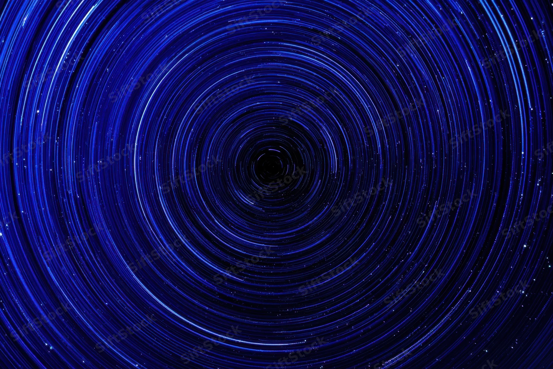 Circular blue light trails from stars rotating in the night sky