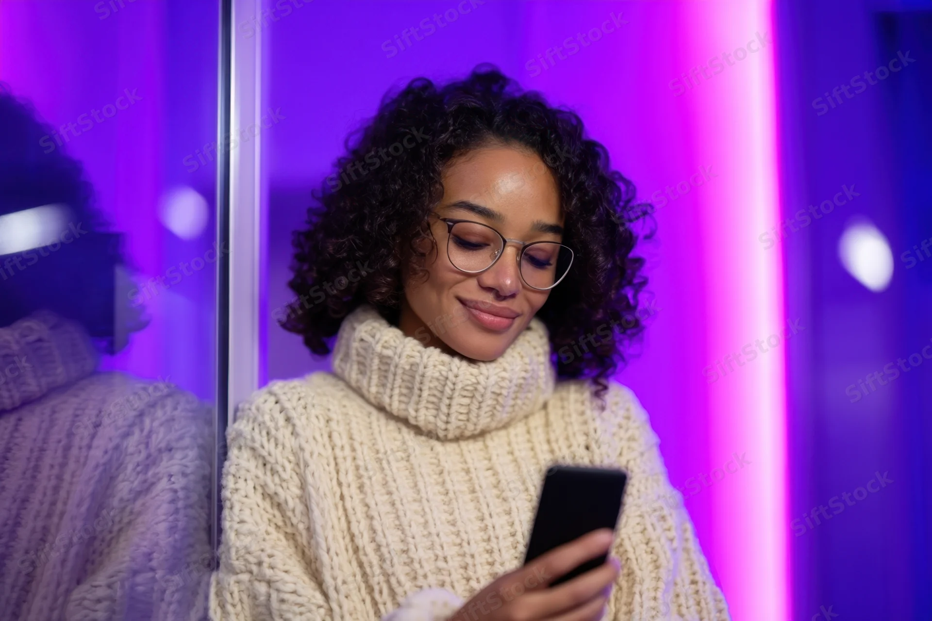 Young woman smiling while using smartphone in neon-lit indoor space