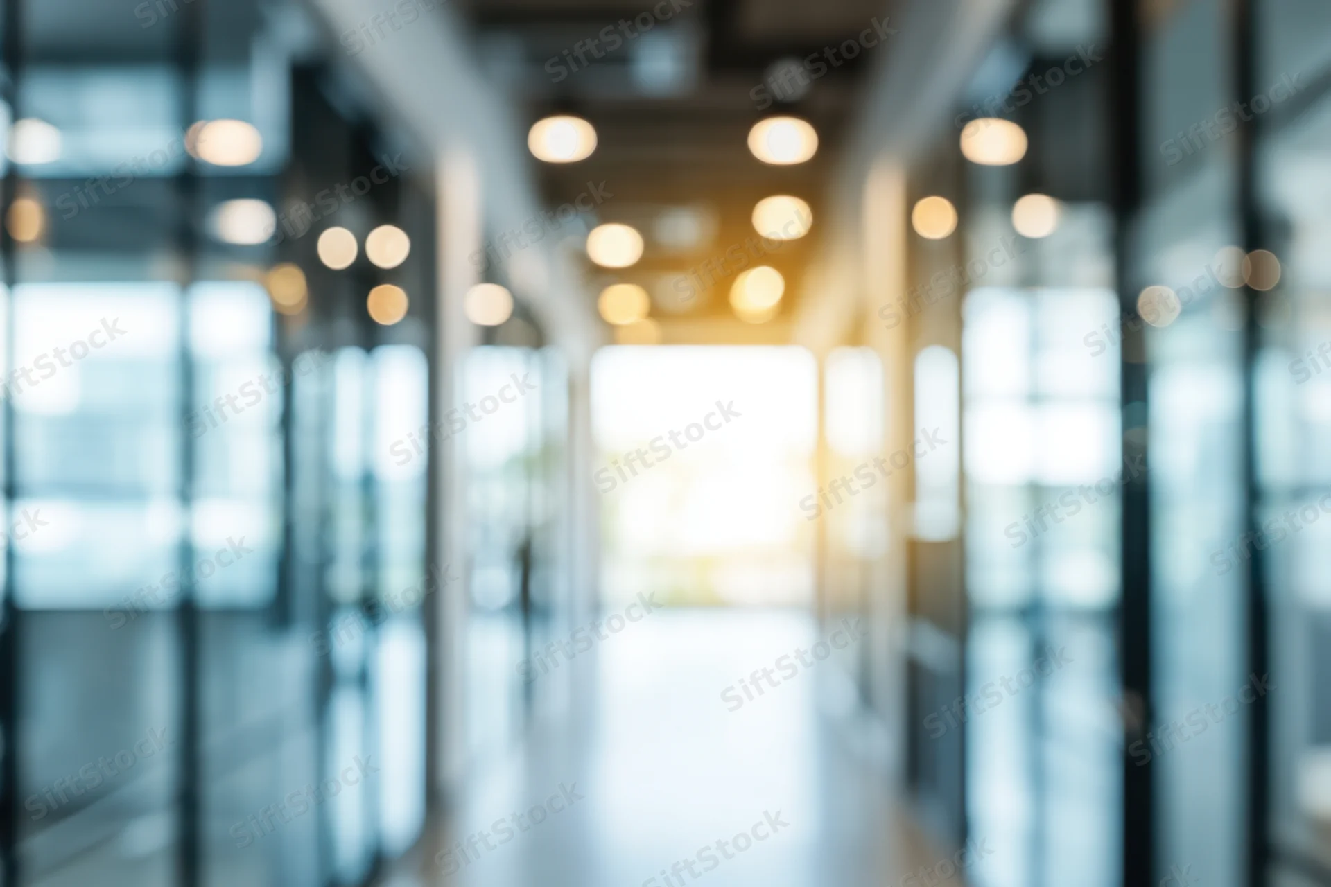 Blurred modern office corridor with glass walls and bright natural light