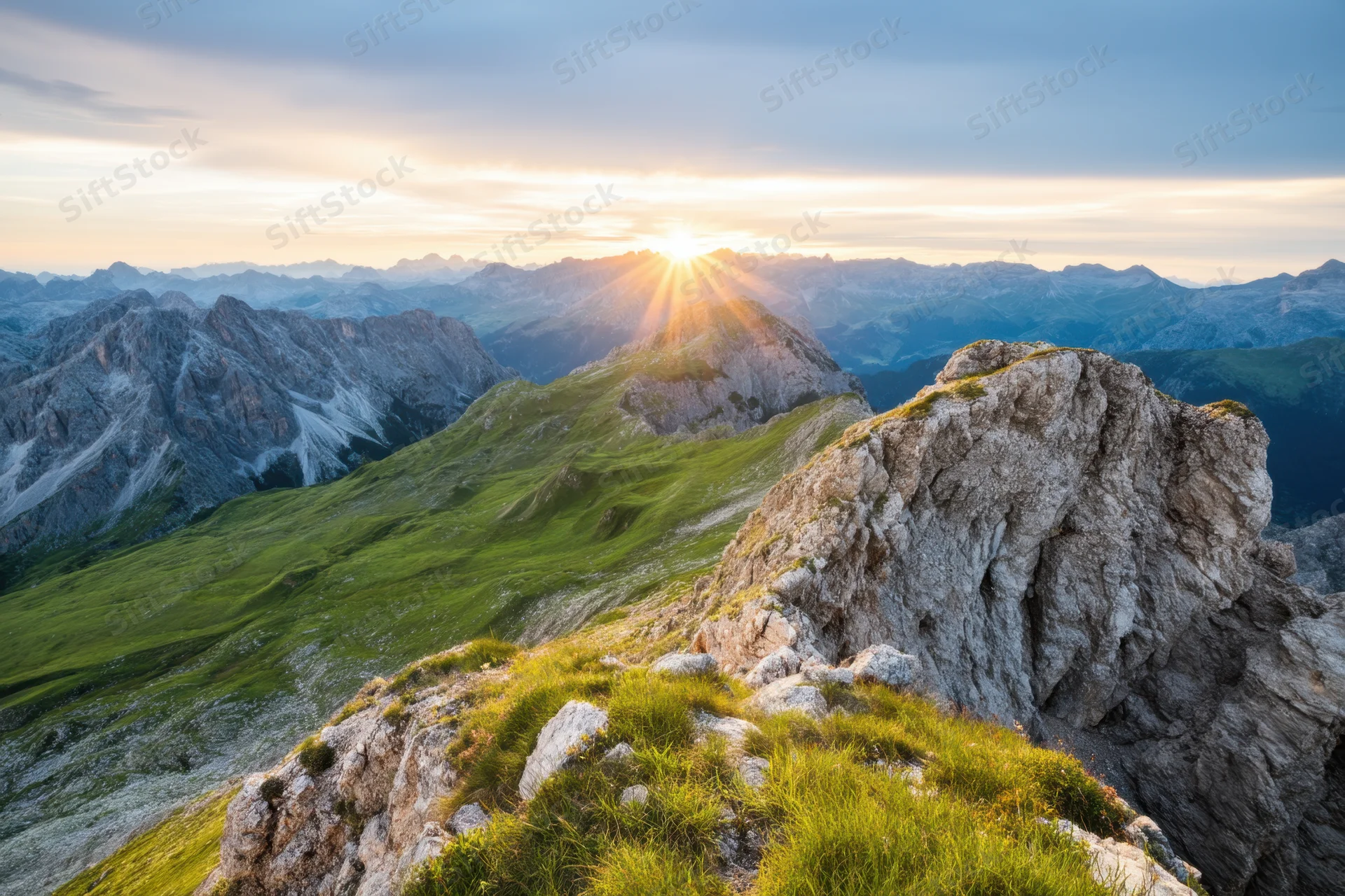 Sunrise over alpine mountain range with rocky peaks and green valleys