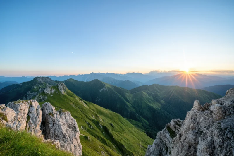 Mountain peak view at sunrise over green valleys and rocky ridges