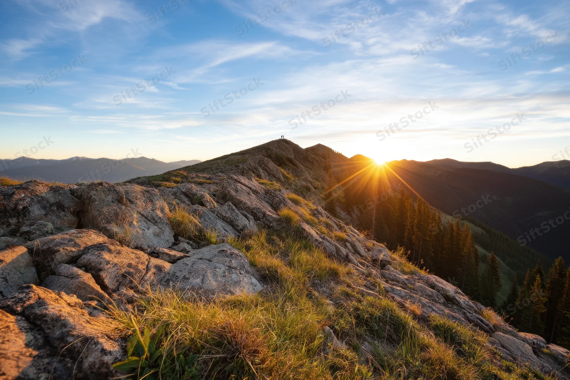 Sunrise over a rocky mountain peak with forested valley below