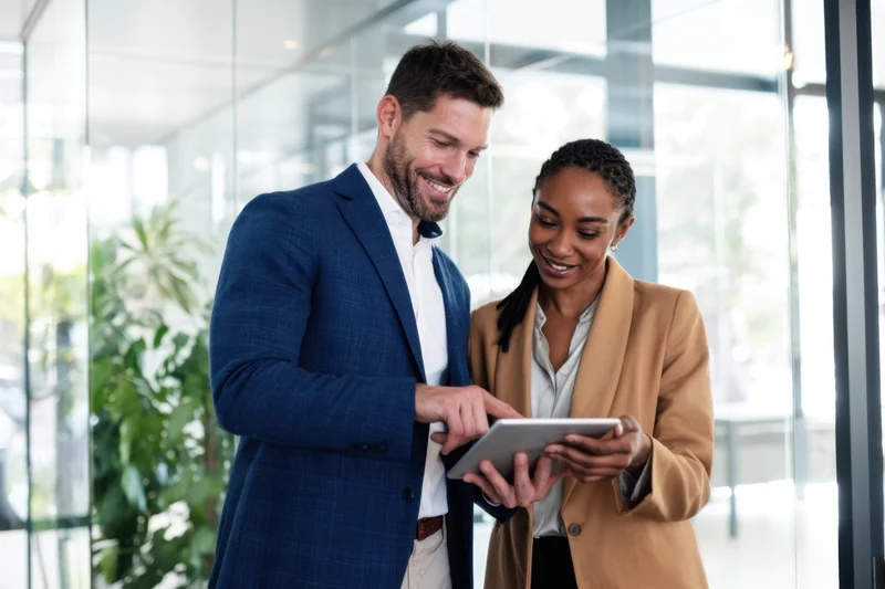 Two business professionals collaborating on a tablet in a modern office