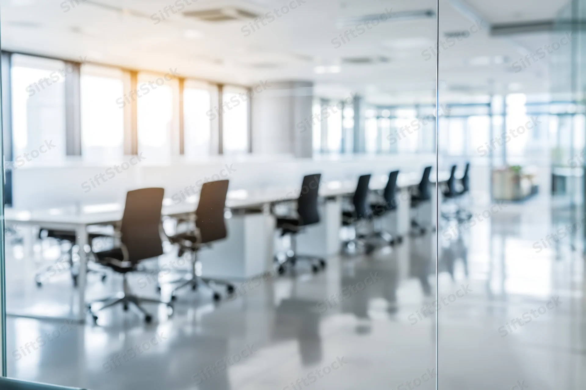 Modern office conference room with glass walls and meeting chairs arranged around a long table