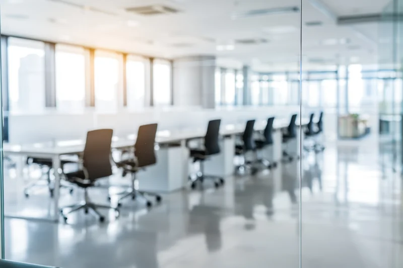 Modern office conference room with glass walls and meeting chairs arranged around a long table