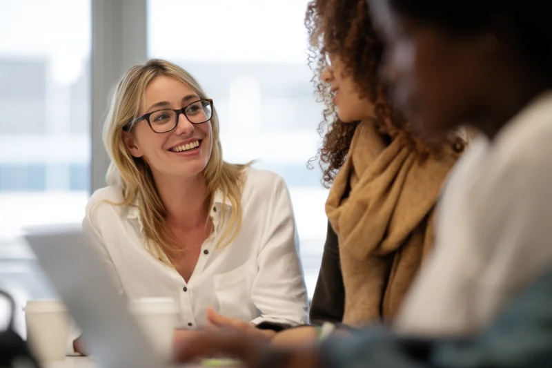 Woman smiling during a meeting with colleagues at an office table