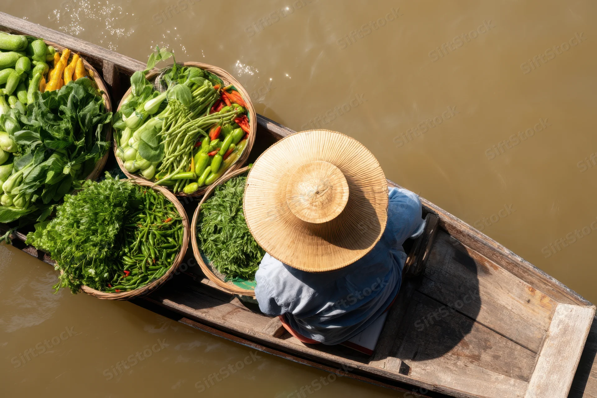 Vendor in a wooden boat filled with baskets of fresh vegetables on a river