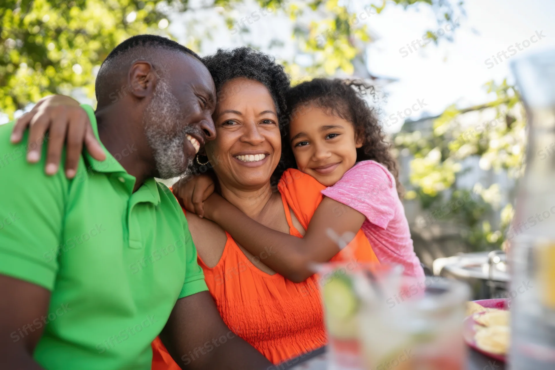 African family embracing outdoors at a garden gathering with drinks and food on the table