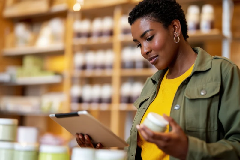 Young woman using tablet to check skincare product inventory in store
