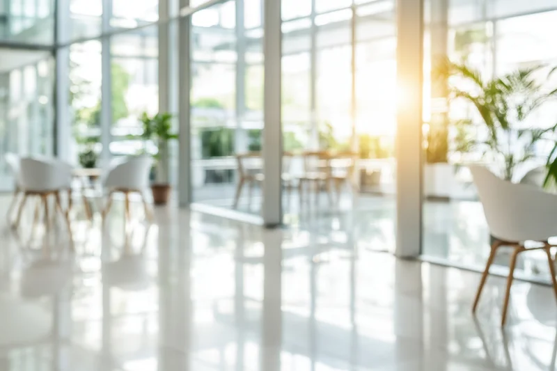 Bright modern office interior with floor-to-ceiling glass walls and white chairs on polished floor