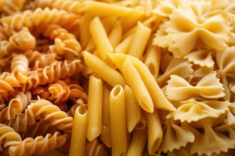 Close-up of fusilli, penne and farfalle dry pasta arranged in a mixed display