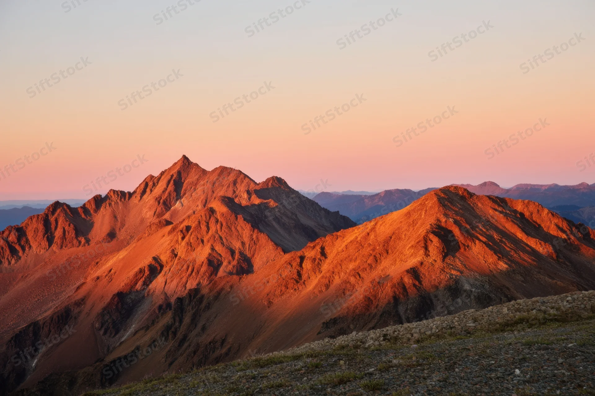 Rugged mountain range illuminated by golden hour light at sunset