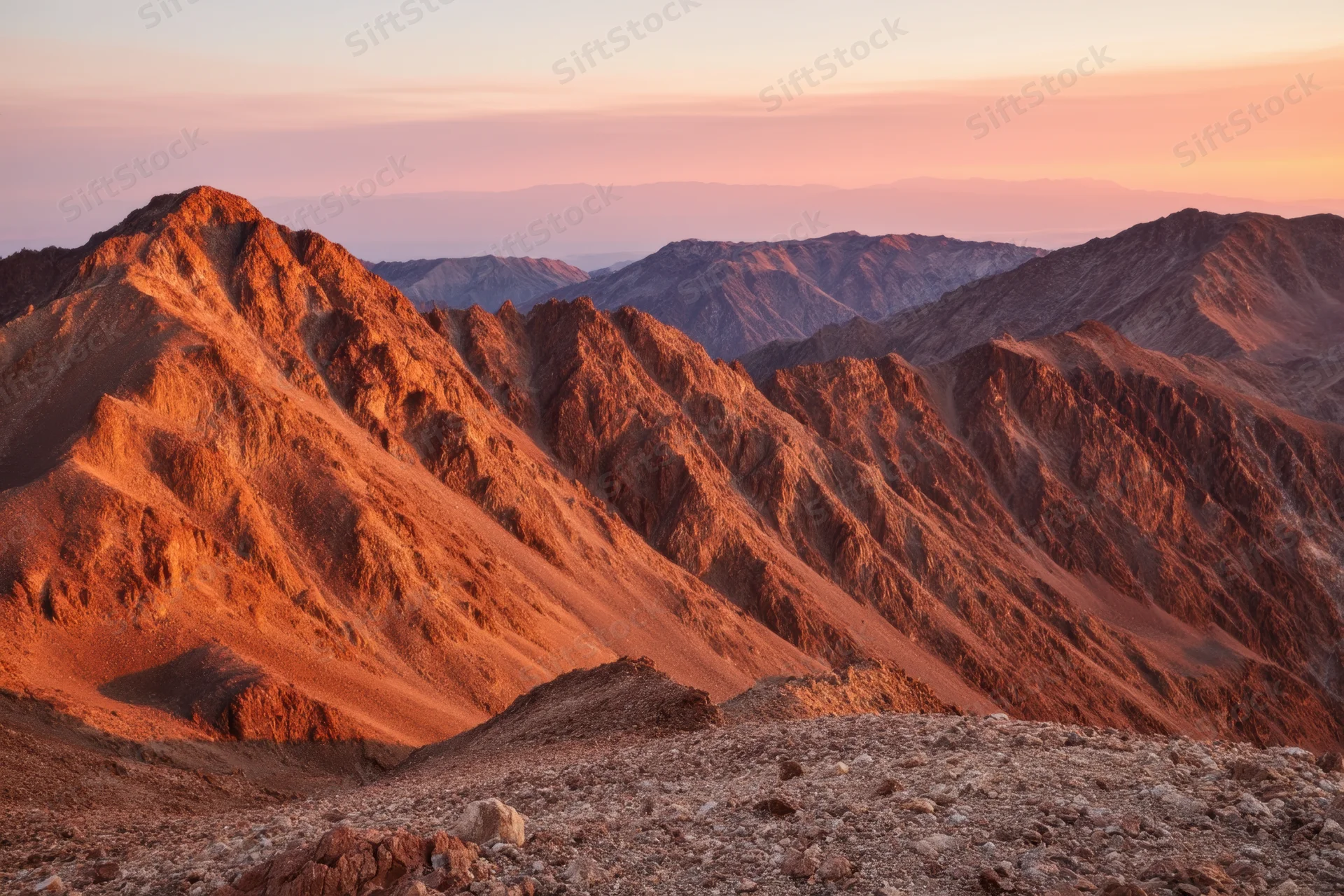 Rugged mountain range under golden hour light with layered ridges and arid terrain