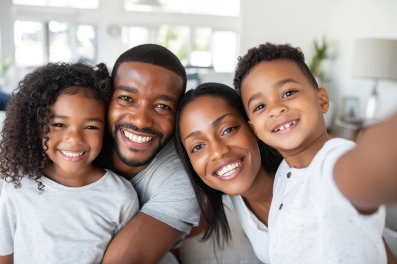 Family of four smiling closely together for a selfie in a bright living room