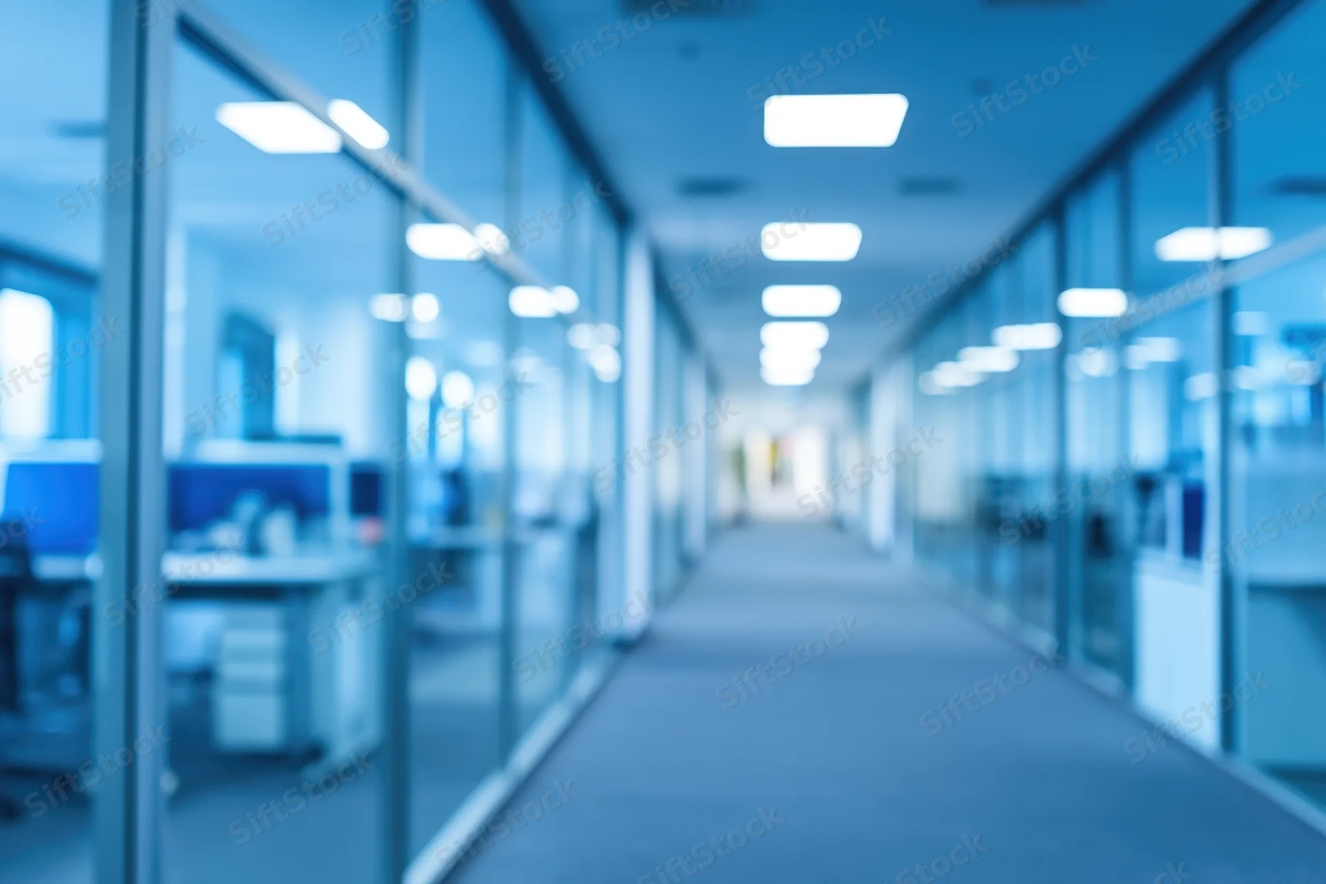Long modern office corridor with glass partitions and fluorescent lighting, viewed from hallway perspective