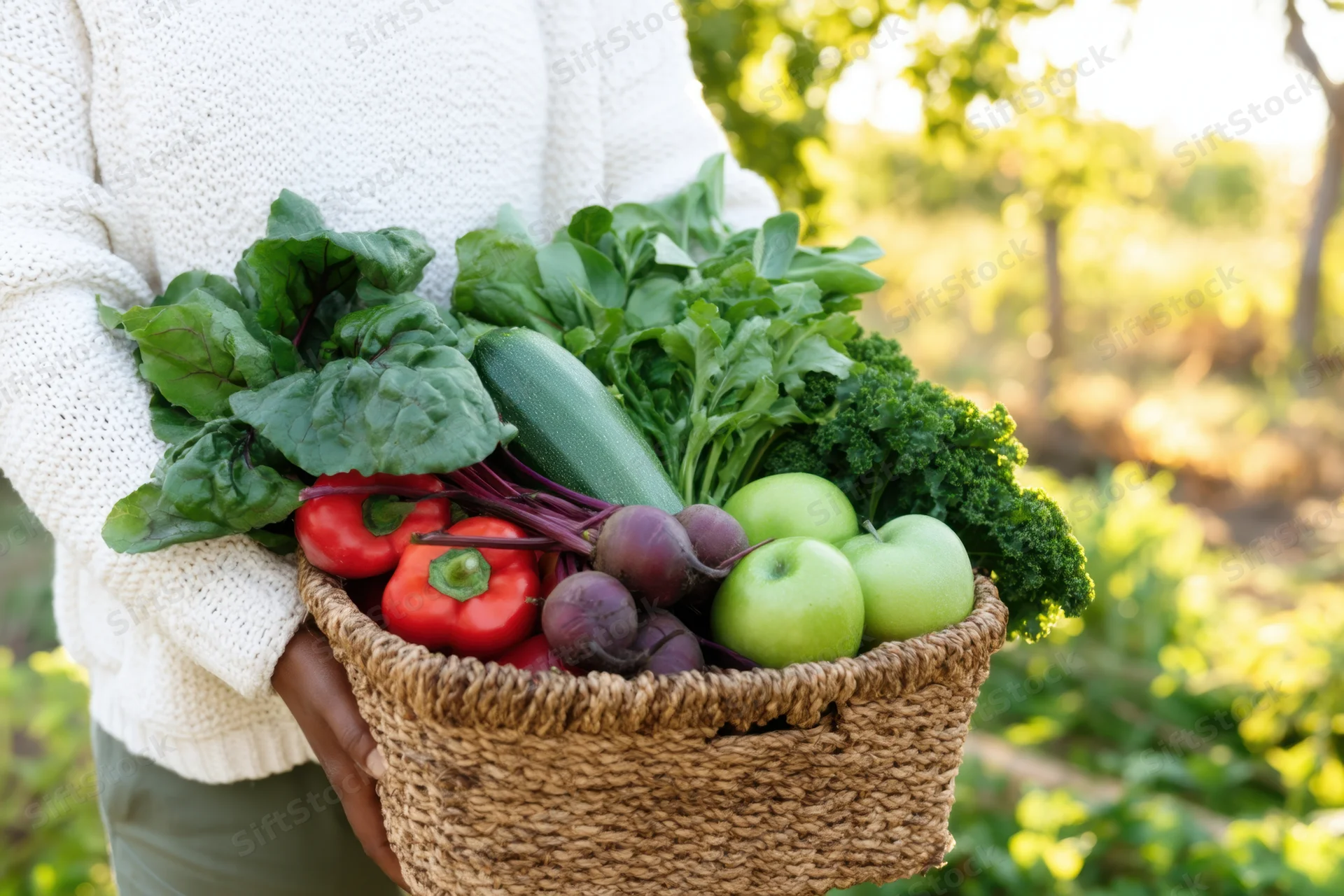 Woman holding a woven basket filled with fresh vegetables and fruits in a garden