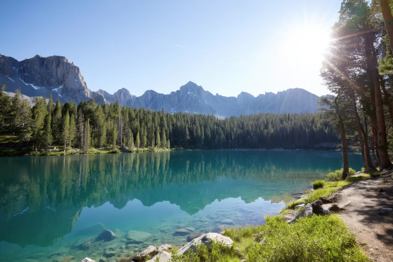 Alpine lake with crystal turquoise water reflecting mountains and forest under clear blue sky