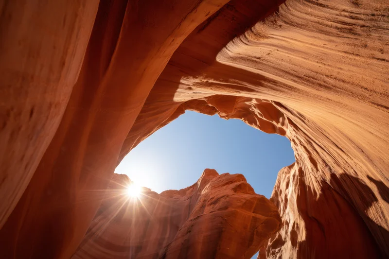 View from inside a slot canyon looking up through a natural arch at the sunlit sky