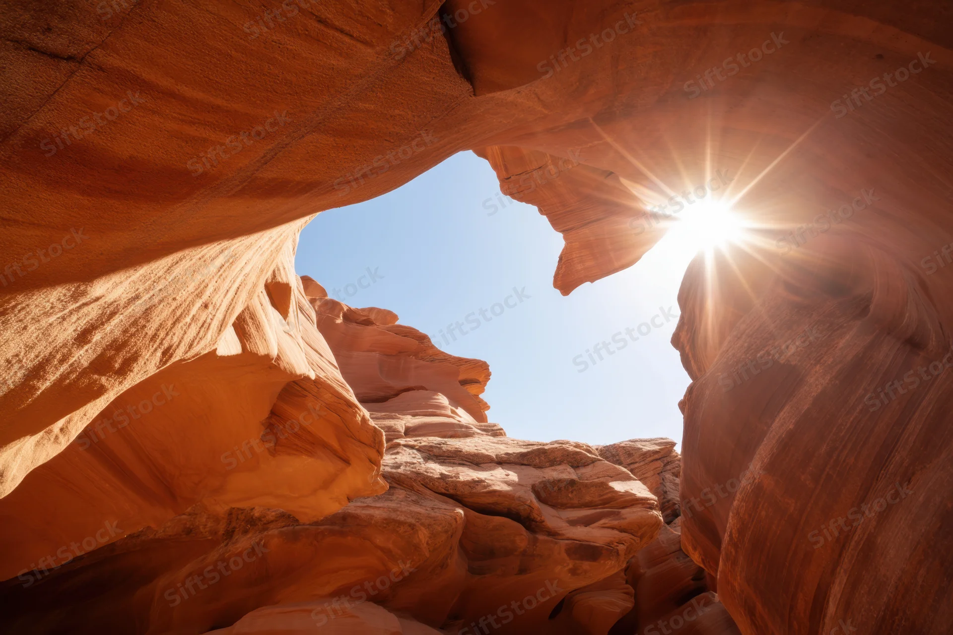 Sunlit slot canyon with smooth orange-red sandstone walls and sky visible through opening