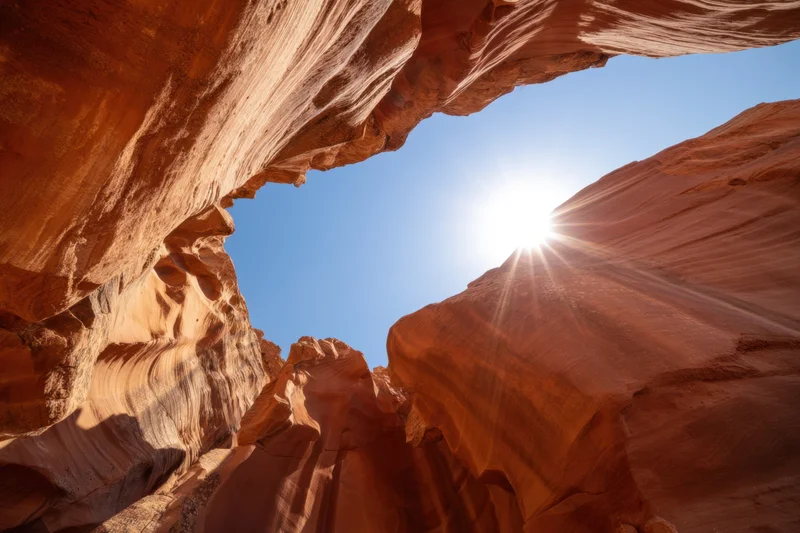 Sunlit slot canyon with smooth orange-red sandstone walls under blue sky