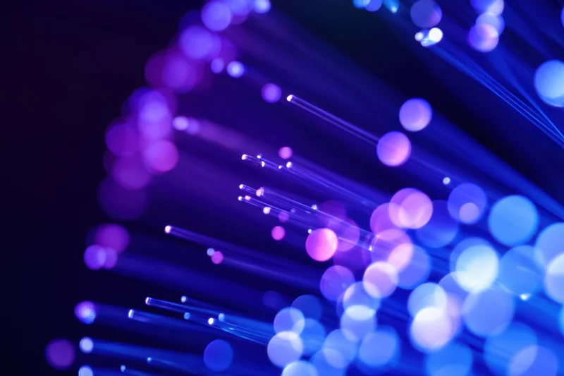 Glowing blue and purple fiber-optic light trails against dark background