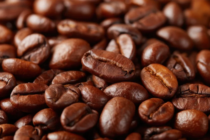 Closeup of roasted coffee beans filling the frame with glossy dark brown texture