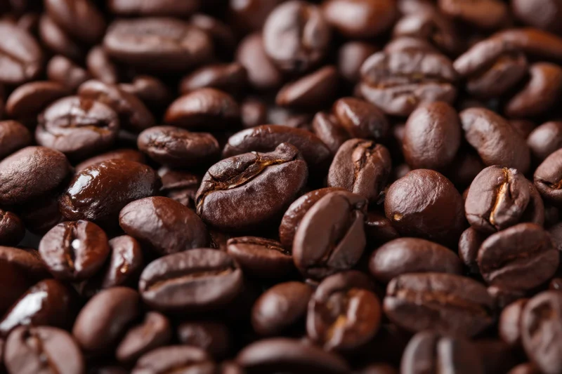 Closeup of roasted coffee beans filling the frame with glossy dark brown surface