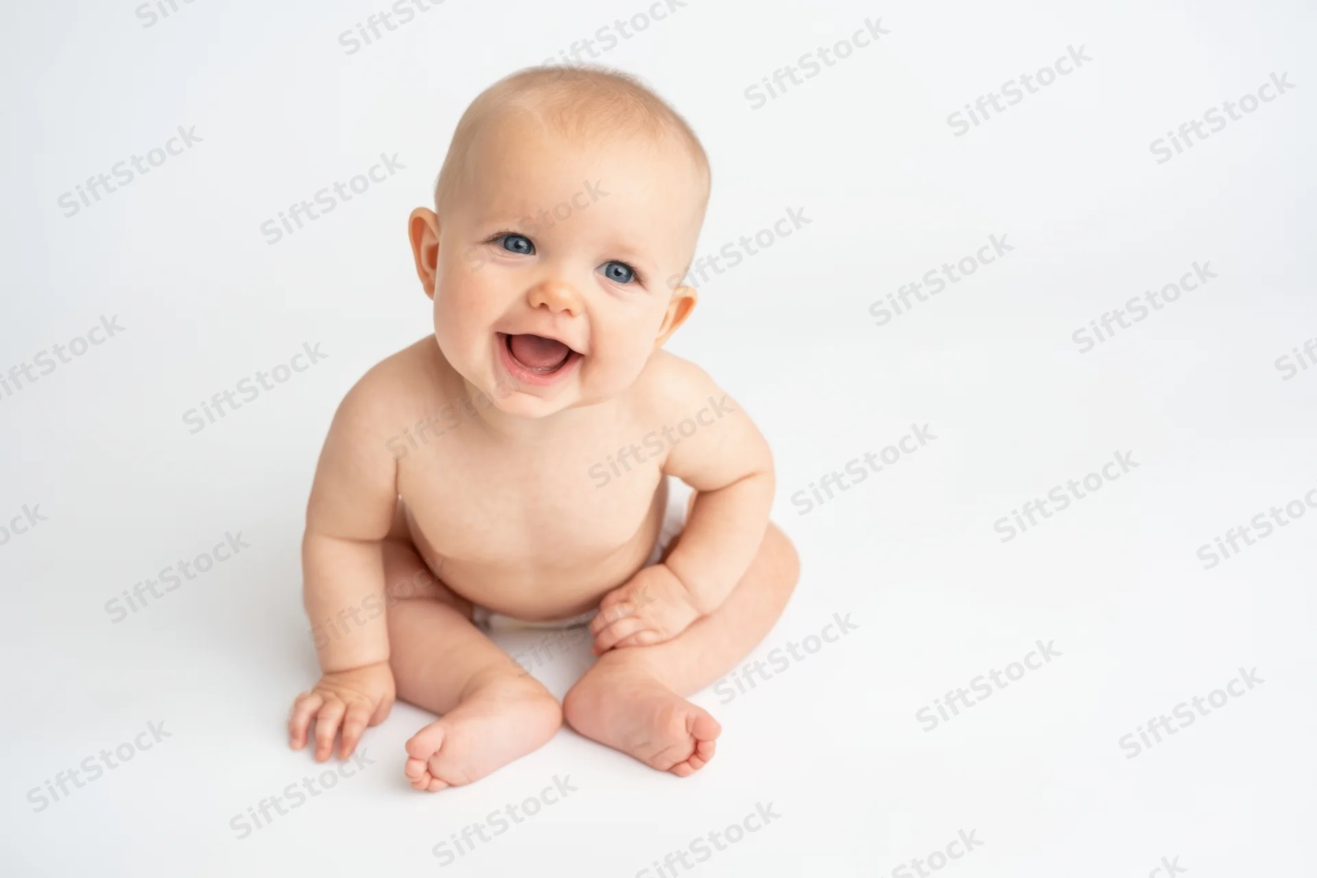 Baby sitting on white studio background smiling with open mouth