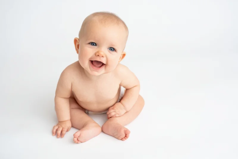 Baby sitting on white studio background smiling with open mouth