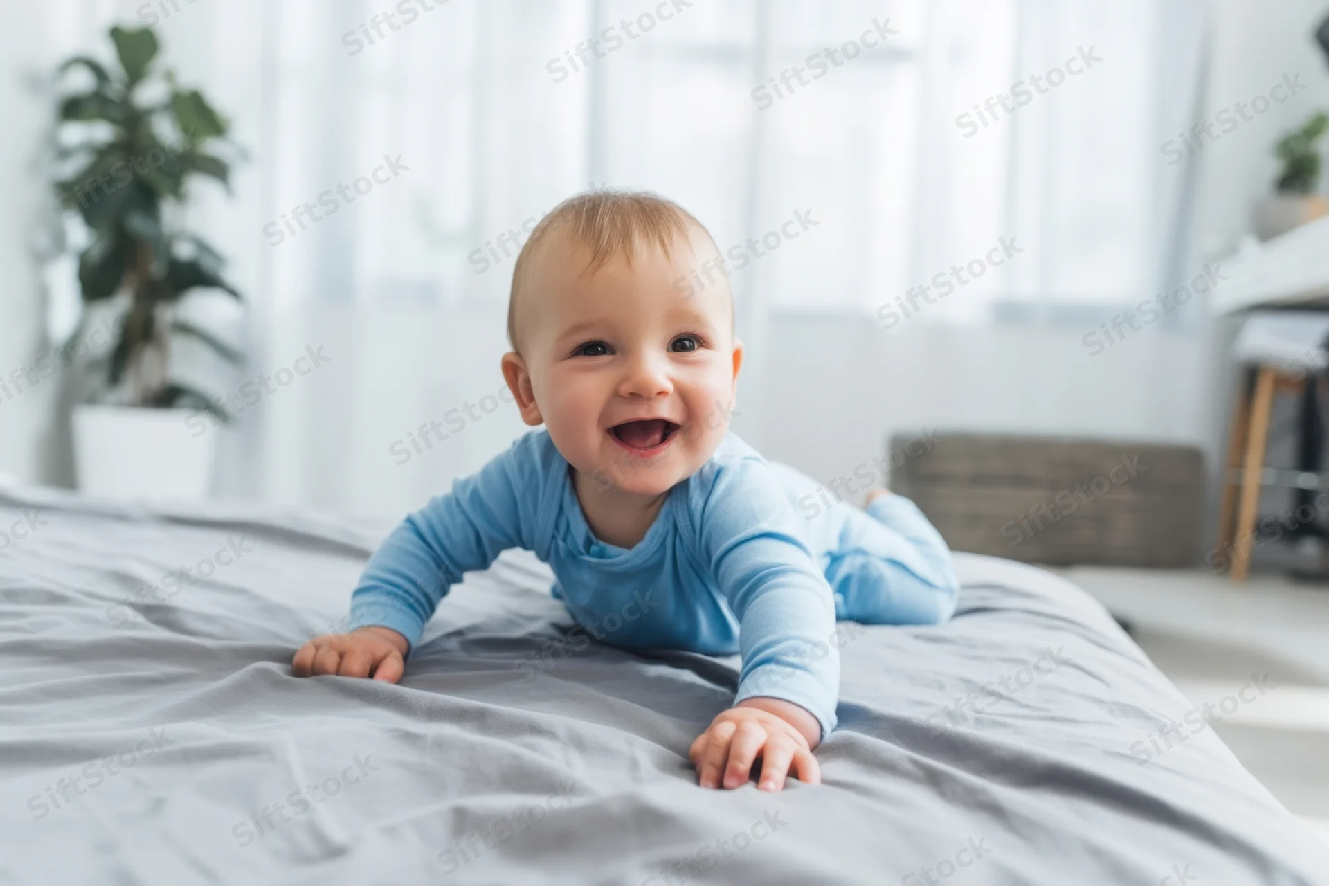 Baby crawling on gray bed in bedroom smiling