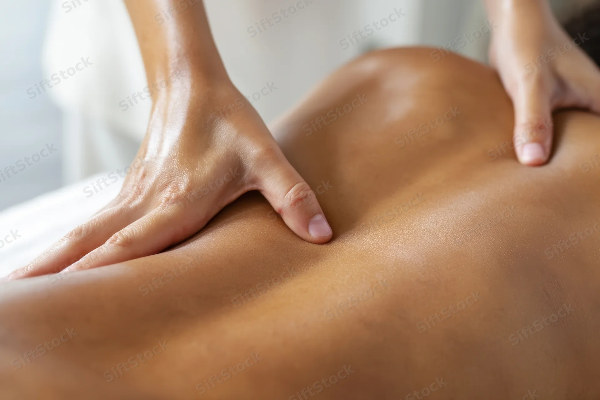 Hands massaging a bare back in a spa setting