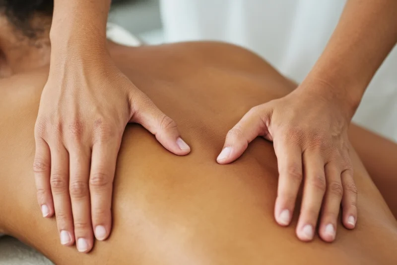 Hands massaging a bare back with fingers applying pressure in a therapy session