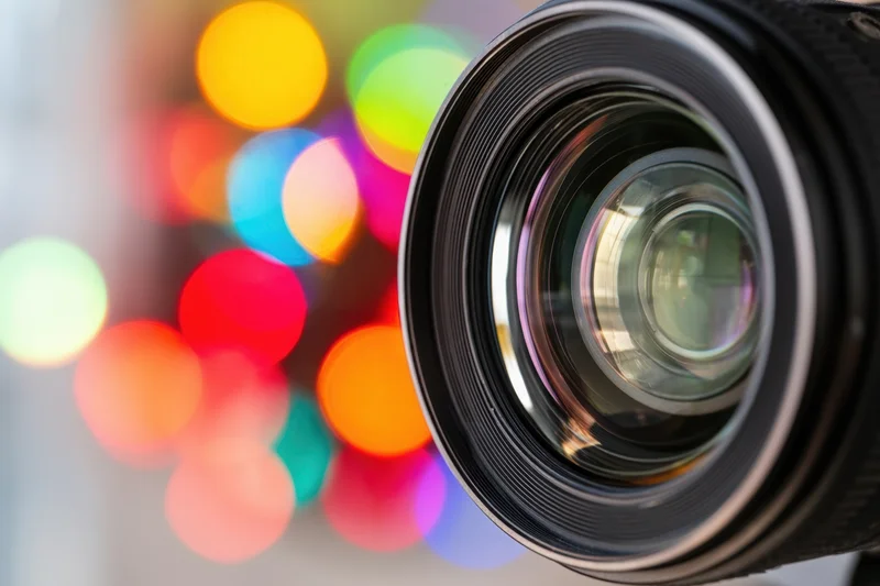 Close-up of a camera lens with colorful bokeh lights in the background