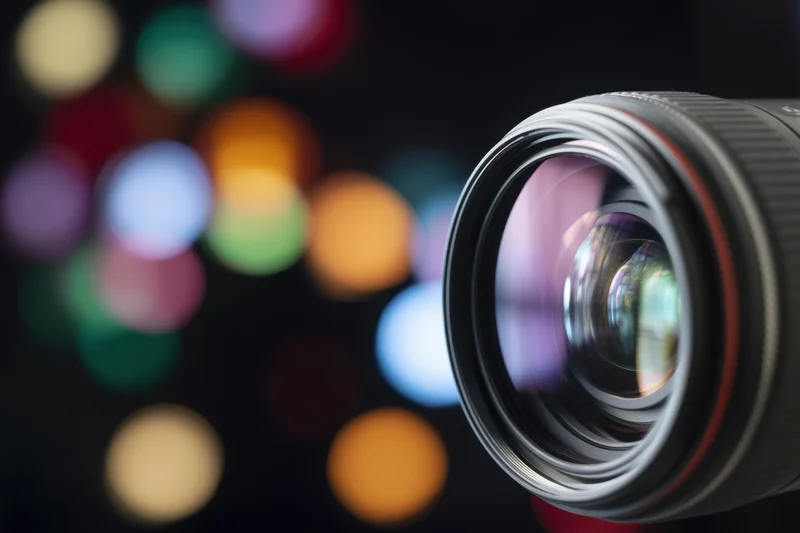 Close-up of a camera lens with colorful bokeh lights in the background