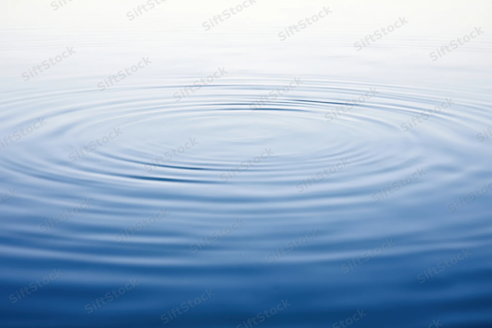 Circular ripples spreading across a calm blue water surface