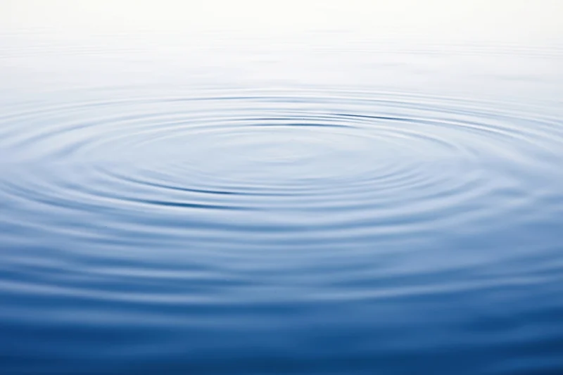 Circular ripples spreading across a calm blue water surface