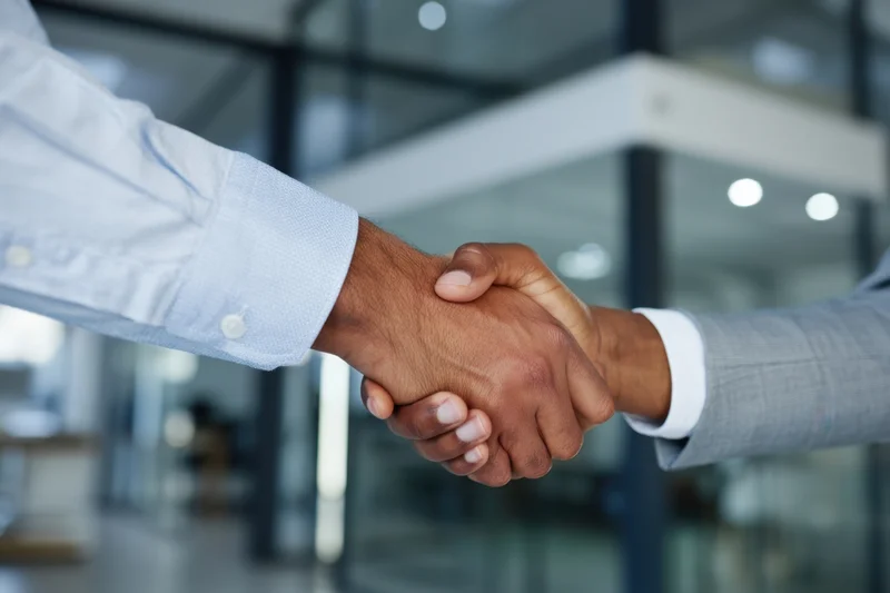 Two professionals shaking hands in a modern office interior