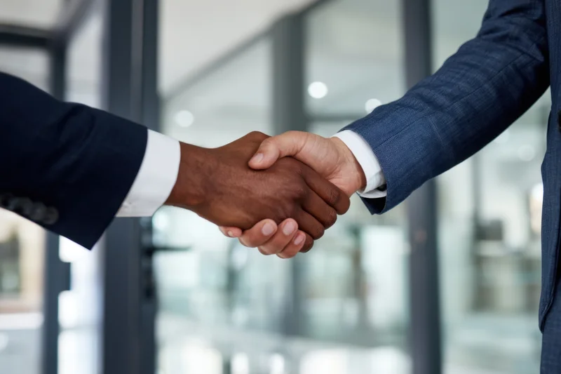 Two professionals shaking hands in a modern office interior