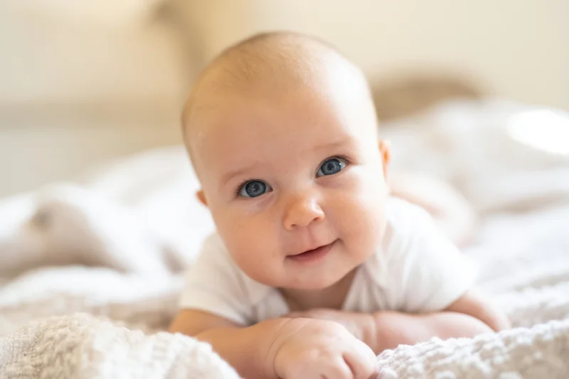 Baby lying on tummy on soft textured blanket in bedroom