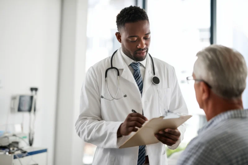Doctor in white coat writing on clipboard during patient consultation in clinic